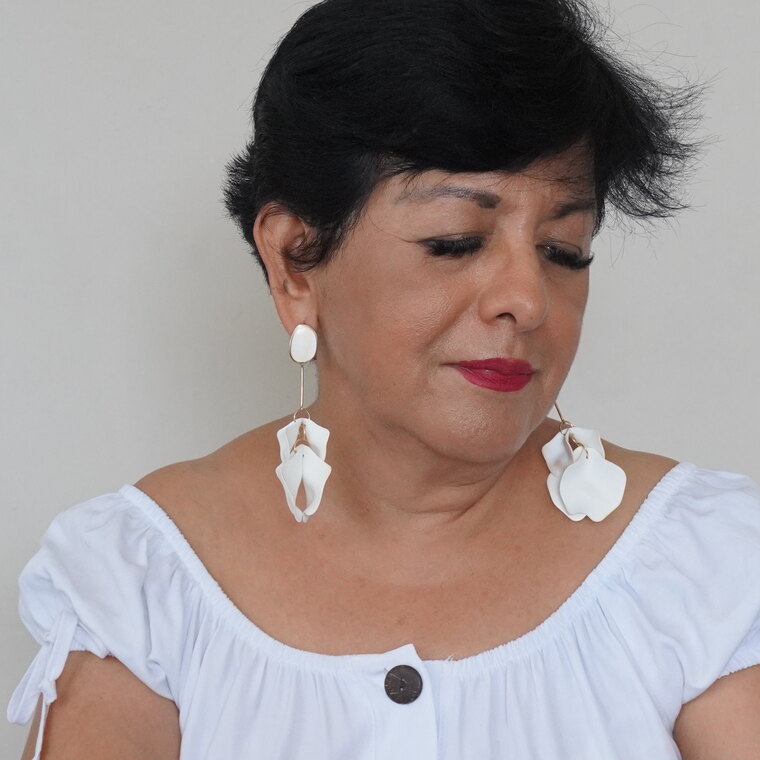 Maricela lee, concentrada, con la mirada baja sobre las páginas de un libro abierto