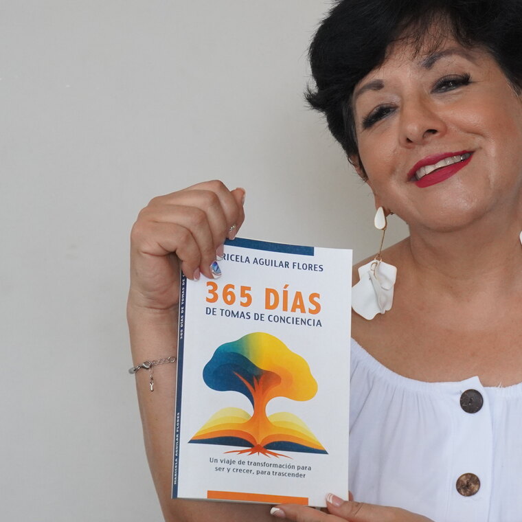 Maricela sostiene entre sus manos su libro 365 días de tomas de conciencia